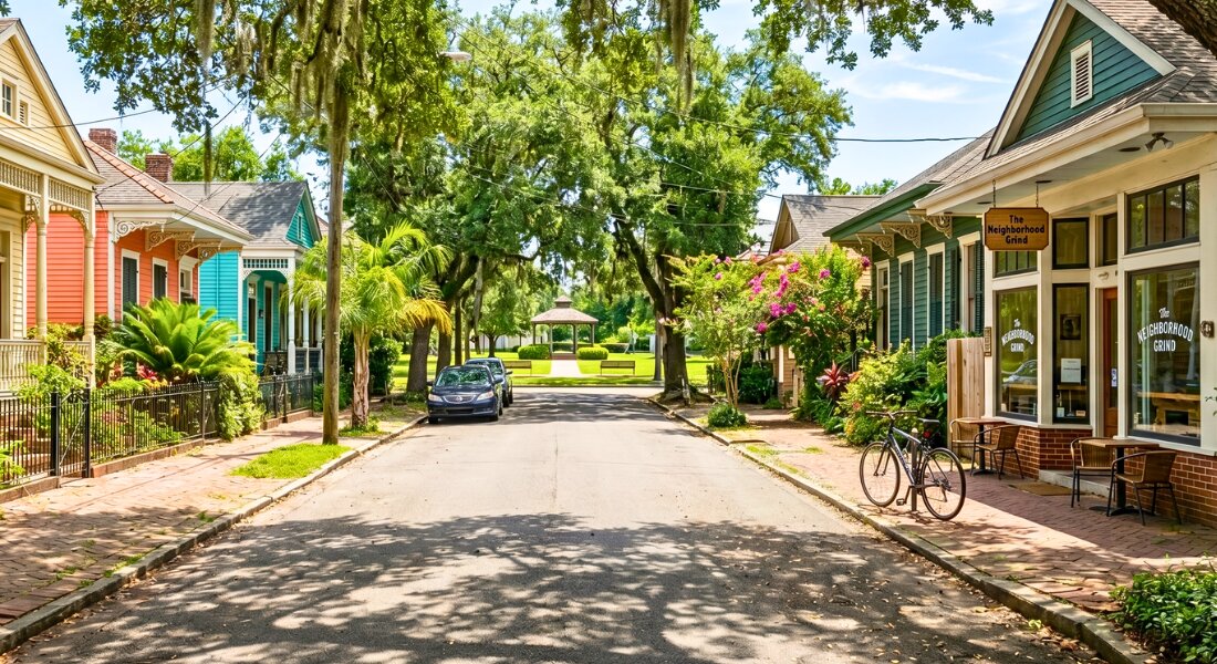 Quiet tree lined New Orleans neighborhood with historic homes on a bright summer day.